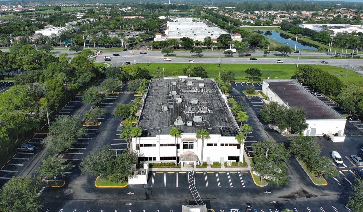 Drone aerial photo of a commercial site showing office buildings, roofs, and parking areas