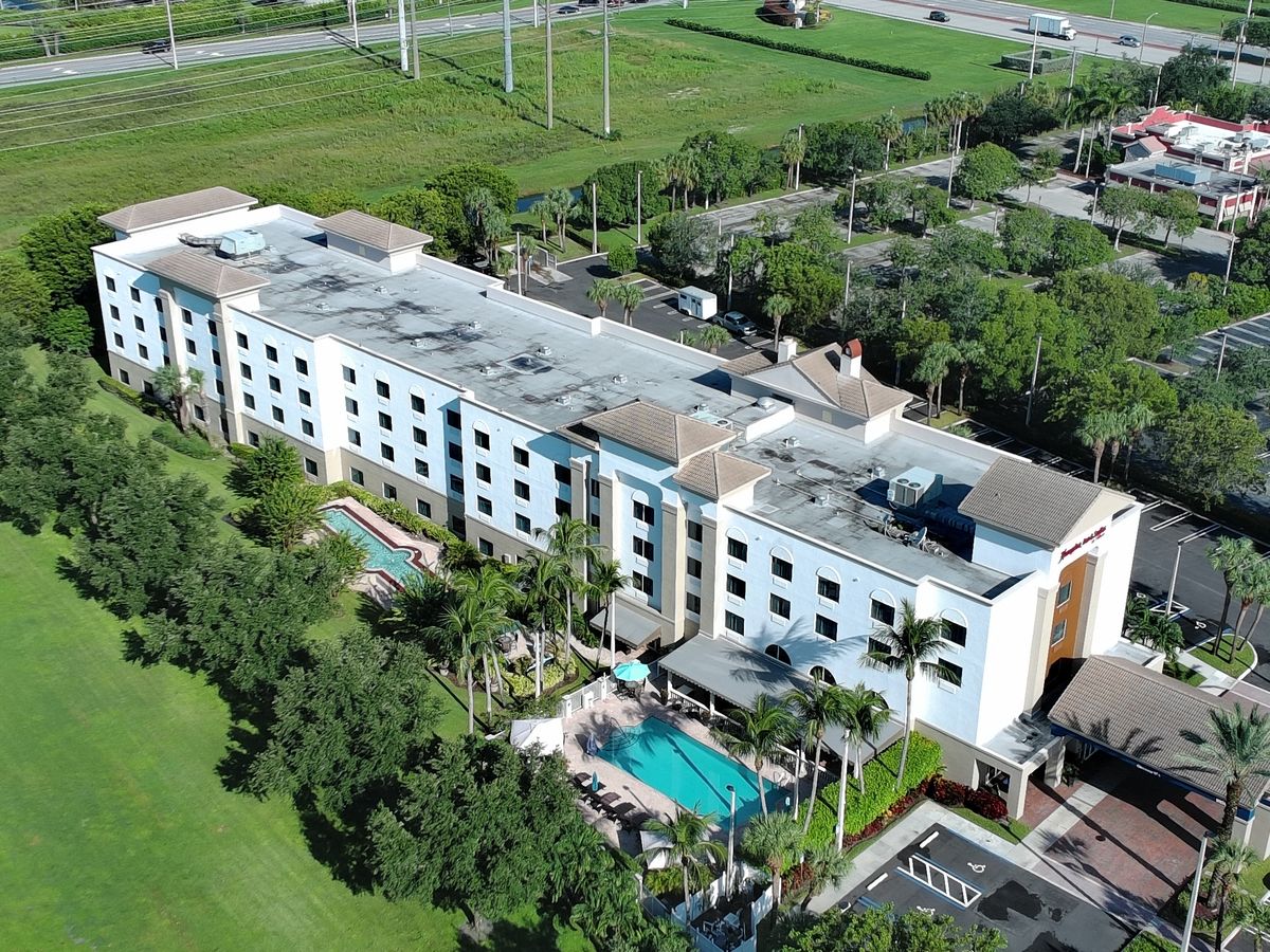 Drone aerial photo of a hotel property showing the building, pool, and landscaped grounds
